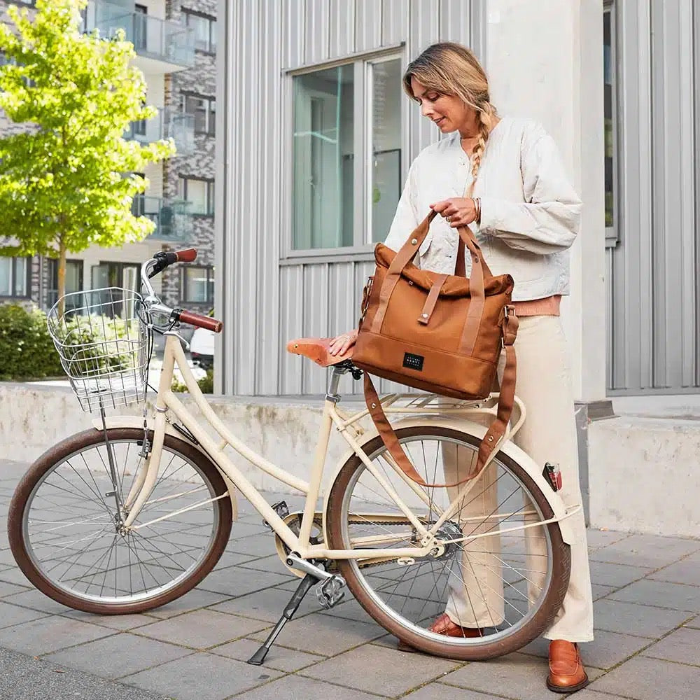 Frau nimmt City Bike Satchel in Braun von Weather Goods Sweden vom Fahrrad