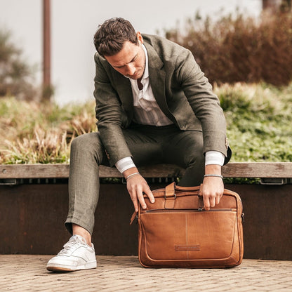 Laptoptasche Seth Cognac – Mann öffnet Tasche auf Bank | The Chesterfield Brand